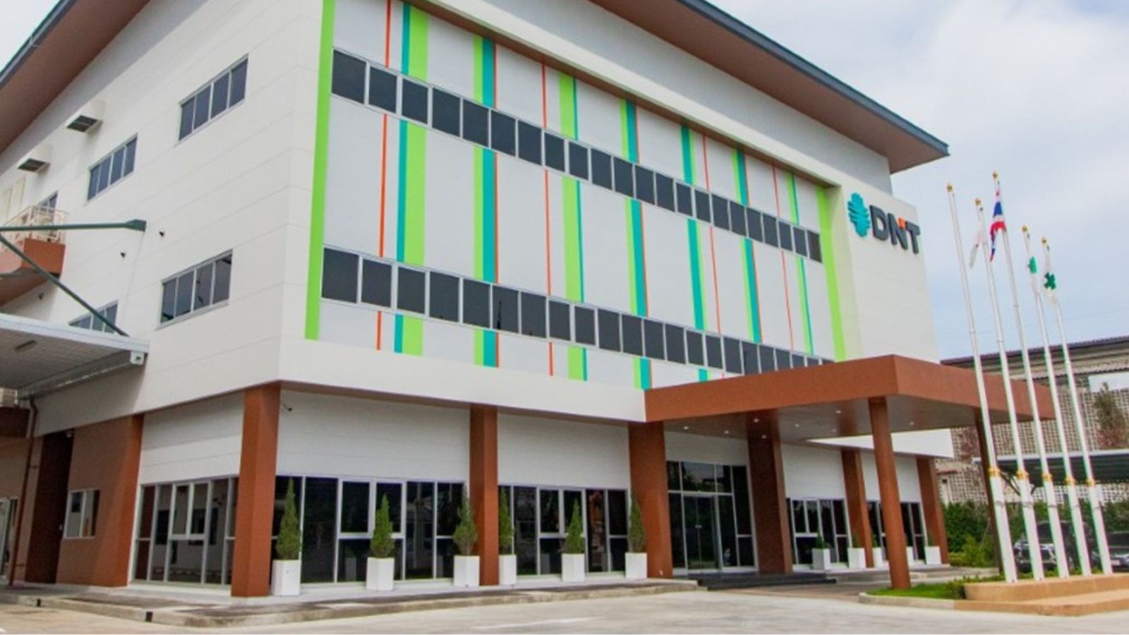 Thai DNT Paint building in Chonburi, Thailand, with a white facade, green and orange vertical stripes and the DNT logo